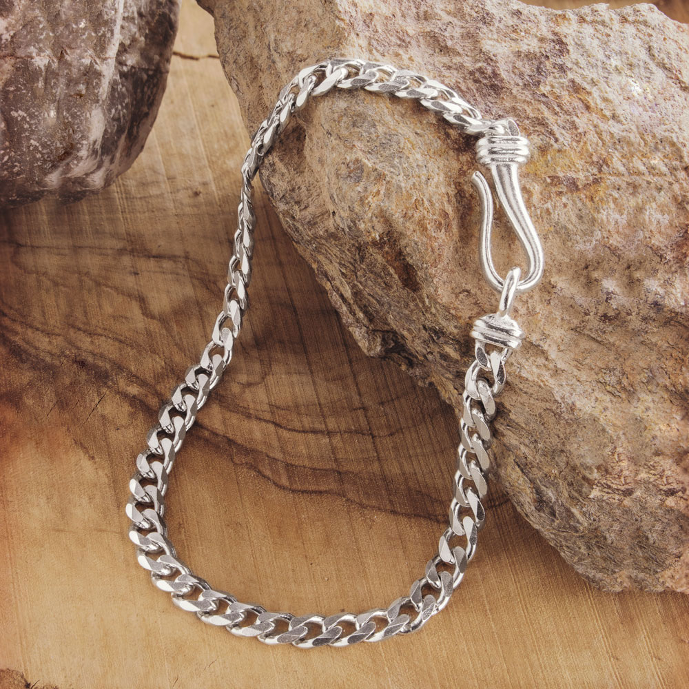 curb chain bracelet with a hook clasp made of sterling silver on a wooden background