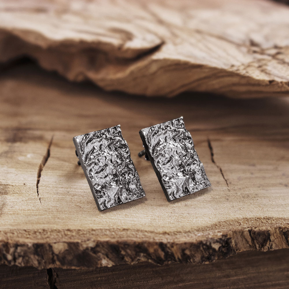 A Pair of Geometric Earrings with an Textured Surface on a Wooden Background