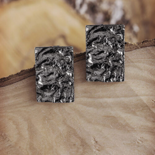 A Pair of Silver Geometric Earrings with an Oxidized Textured Surface on a Wooden Background
