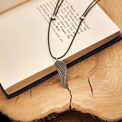 Angel Wing Pendant Necklace in Oxidized Solid Silver laid down on top of a book
