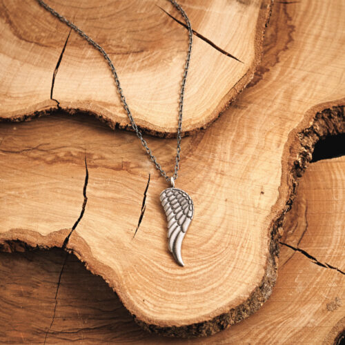 Angel Wing Pendant Necklace in Oxidized Solid Silver displayed on a log
