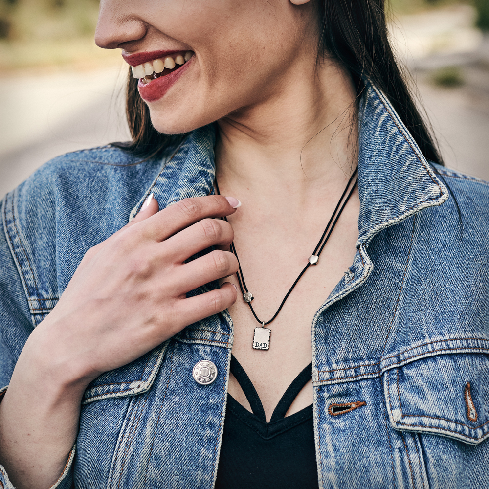 A female model wearing our sterling silver personalized dad pendant with a black cord.
