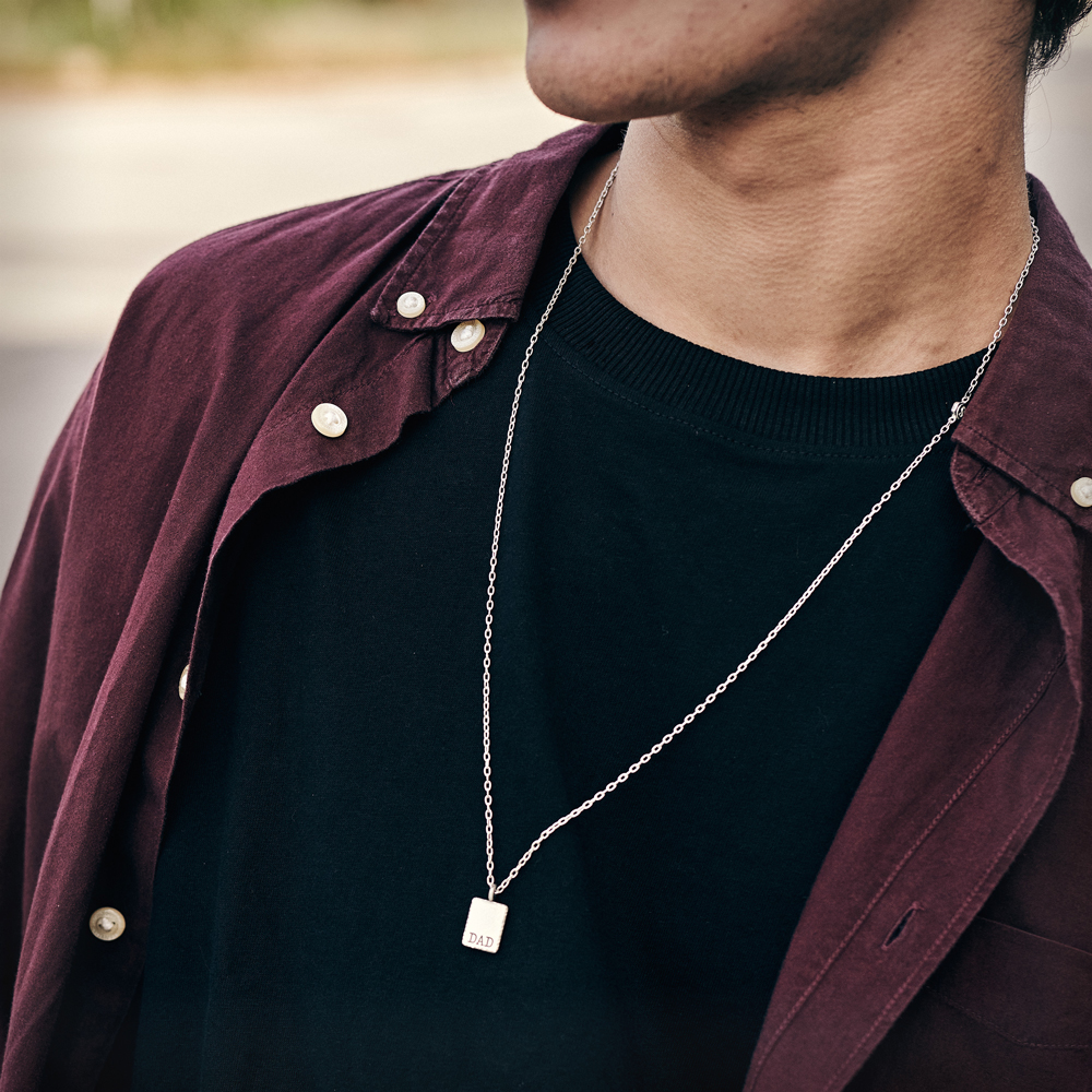 A male model wearing our sterling silver personalized dad pendant with a chain.