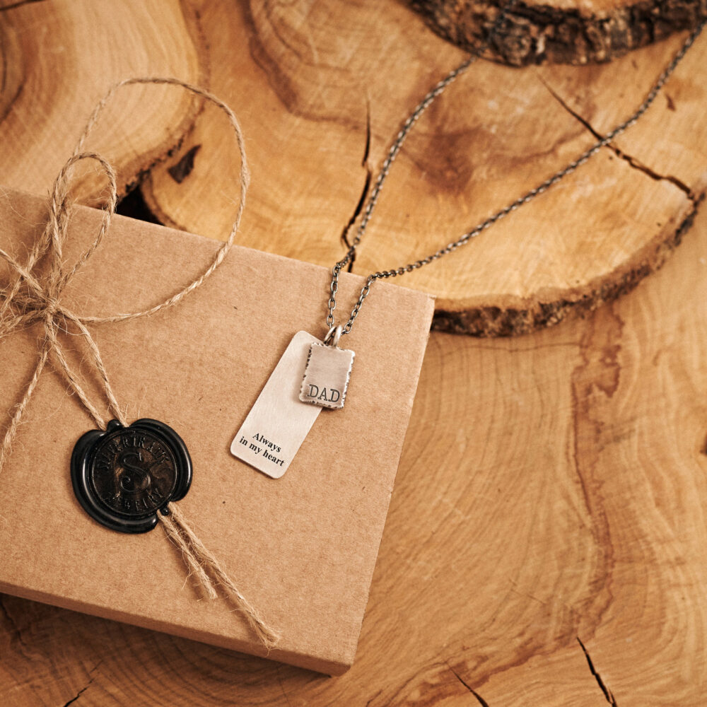 our Personalised Double Small and Large Silver Pendant with a chain displayed on top of the box it comes on.